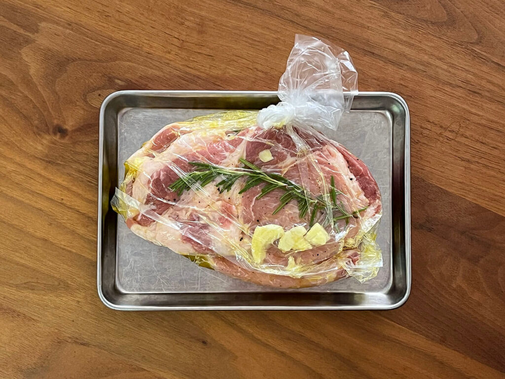 写真：塩コショウした豚肉・にんにく・ローズマリー・オリーブオイルを入れました